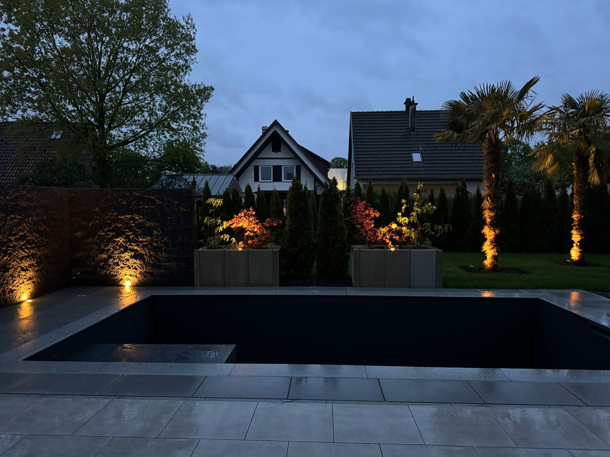 Pool in der Dämmerung mit Beleuchteter Sichtschutzwand und Palmen