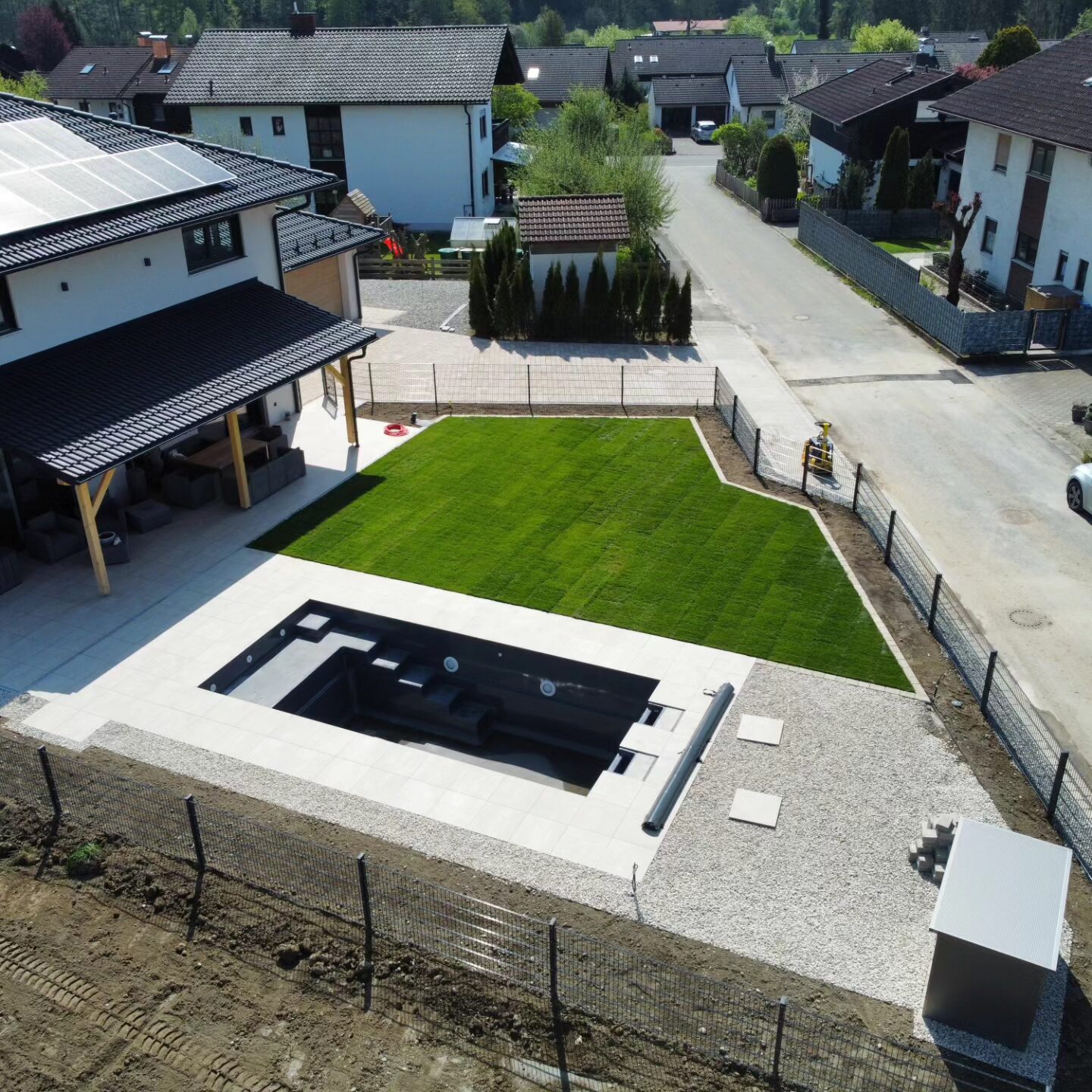 Ansicht von oben auf Pool und Haus mit gepflasterter Umrandung