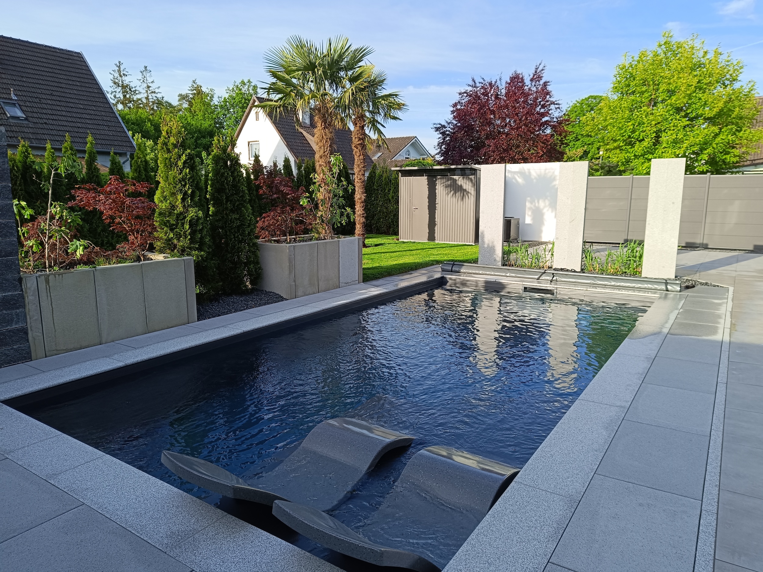 Garten mit großen grauen Bodenplatten, die einen modernen Pool umrahmen (1)